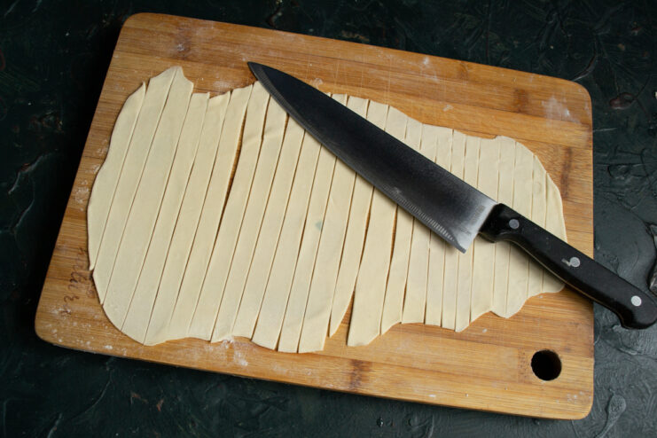Cutting the homemade noodles Cutting the rolled dough into wide strips with a knife