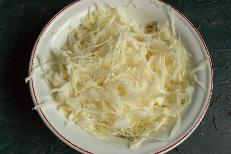 Shredding cabbage for the salad Finely shredded white cabbage in a white mixing bowl