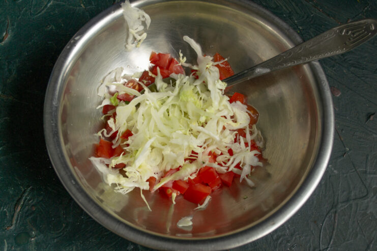 Adding cabbage to the salad Shredded Napa cabbage added to diced tomatoes