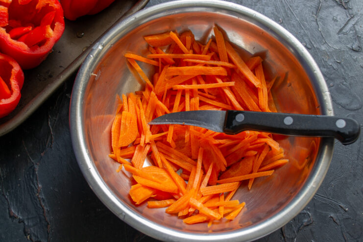 Slicing carrots for the filling Thinly julienned carrots resting in a metal mixing bowl