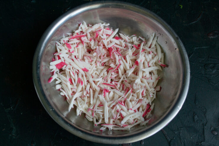 Grating the crab sticks Grated imitation crab sticks in a metal mixing bowl