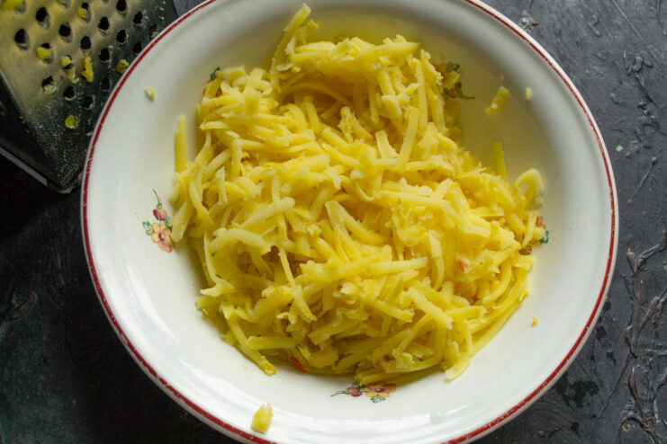 Preparing potatoes Grated boiled potatoes in a light-colored mixing bowl