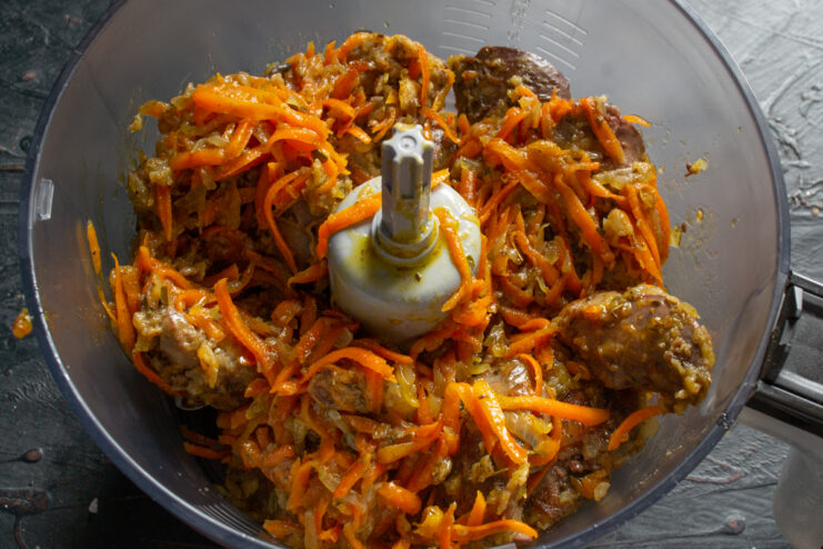 Blending the ingredients Cooked liver and vegetable mixture placed inside a food processor bowl.