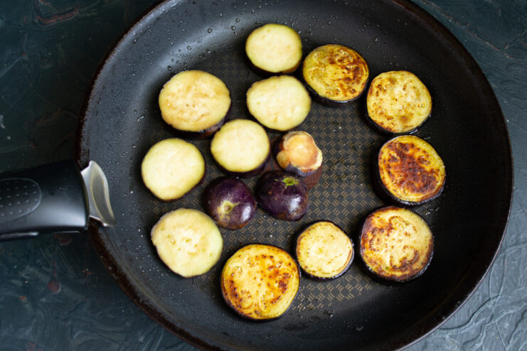 Frying the eggplant Frying sliced eggplant rounds in a hot skillet until golden
