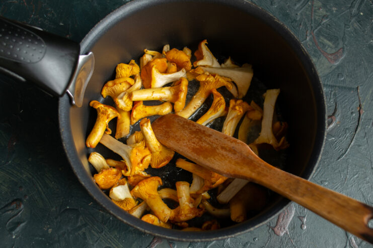 Sautéing the mushrooms Sautéing chanterelles and garlic in a pan with a wooden spatula