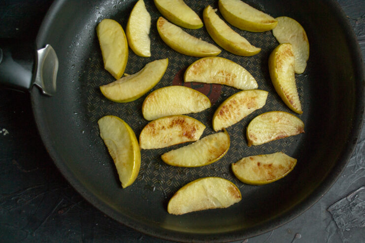 Caramelizing the apples Sautéing apple slices in a skillet with butter