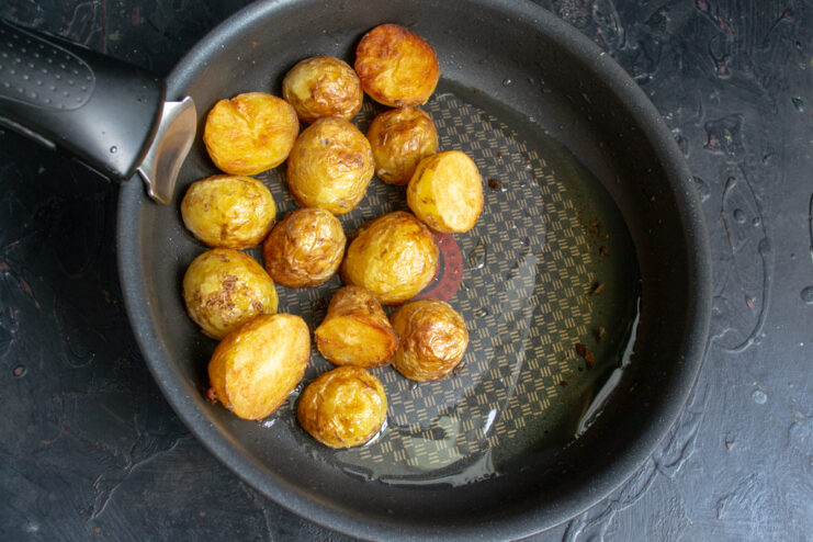 Frying the Potatoes Pan-frying halved parboiled new potatoes in a skillet until they develop a golden brown crust.