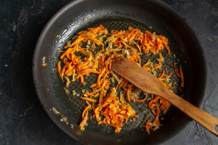Sauteing vegetables for the filling Sauteing grated carrots and chopped onions in a skillet