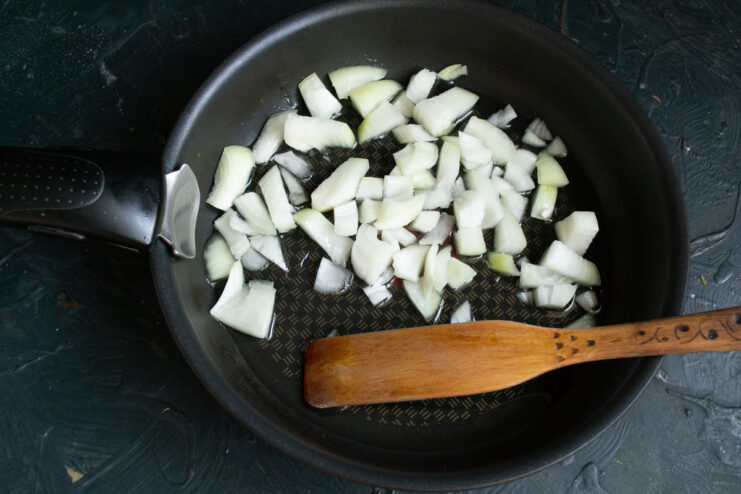 Sautéing finely chopped onion in a skillet with vegetable oil until translucent