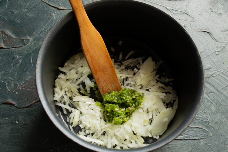 Sautéing onions and spices Finely chopped onions sizzling with spicy adjika paste in a heavy-bottomed pot