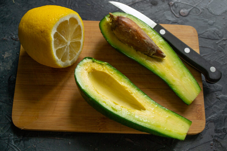 Preparing the avocado Peeled diced avocado and a lemon half resting on a wooden cutting board