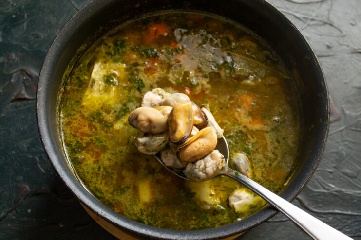 Adding the mussels Shelled mussels held on a spoon right before being added to the simmering soup