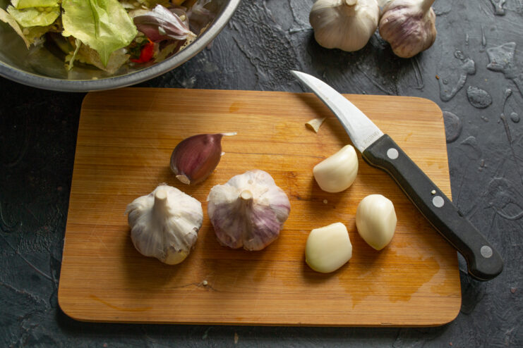 Prepping the garlic Peeled and thinly sliced garlic cloves on a cutting board