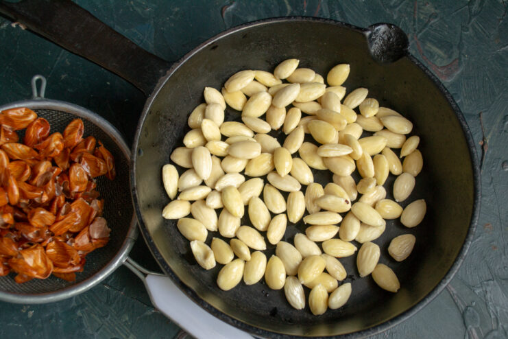 Peeled white almonds spread out on a dry skillet for gentle drying