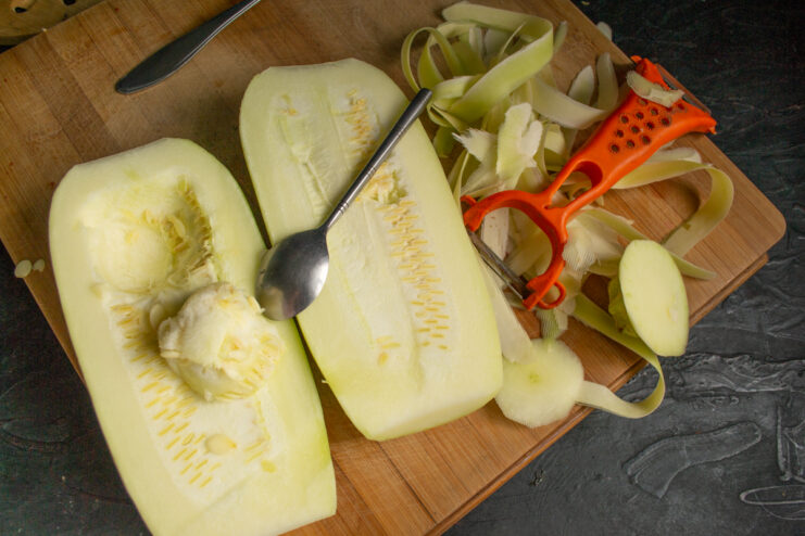 Scooping seeds out of peeled zucchini halves with a spoon