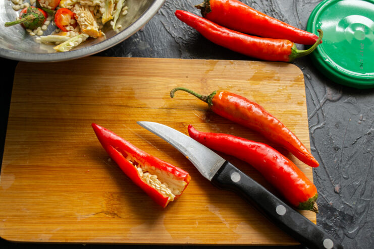 Prepping the hot peppers Slicing open and seeding a red chili pepper with a knife