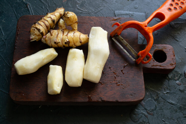 Preparing the Jerusalem artichoke Peeling a Jerusalem artichoke with a vegetable peeler on a board