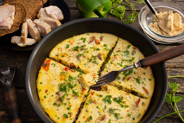 Fluffy powdered egg omelet with vegetables in a skillet