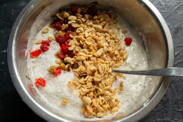Folding in fruits and nuts Nuts and dried berries piled on top of the dough in a bowl