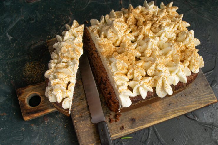 Serving The Cake A sliced piece of dark blackcurrant cake with whipped cream on a wooden cutting board