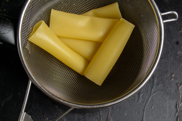 Draining the pasta Parboiled cannelloni tubes draining in a metal mesh strainer
