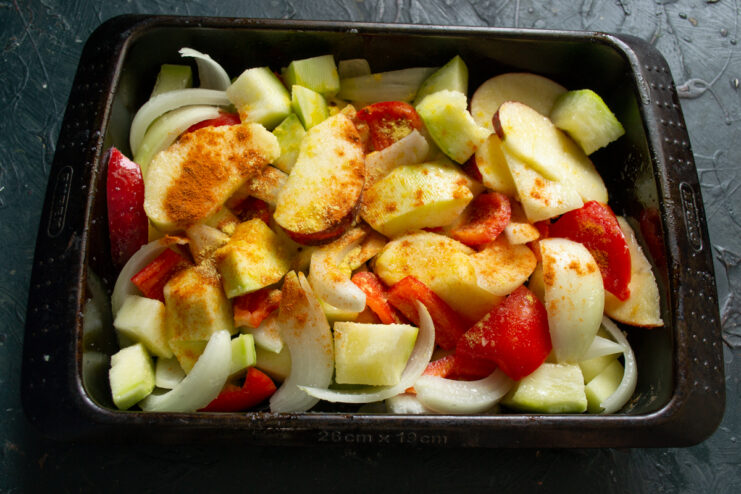 Adding spices to the vegetables Chopped vegetables sprinkled with paprika and asafoetida before baking