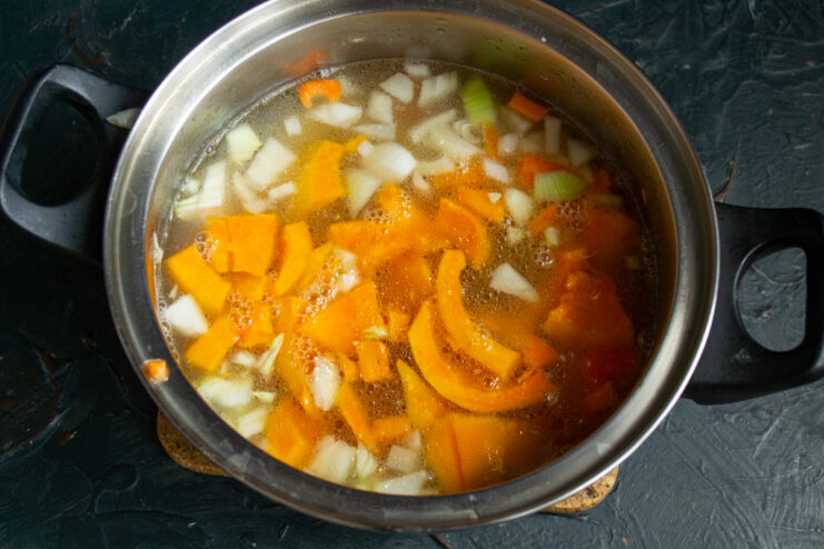 Vegetables in a pot covered with broth before the simmering process begins