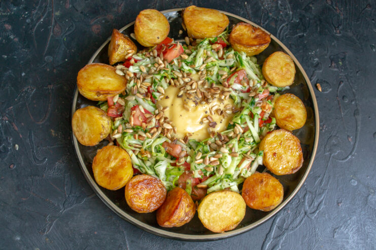 Final Salad Assembly Vegetable salad surrounded by golden pan-fried potatoes and sprinkled with toasted sunflower seeds.