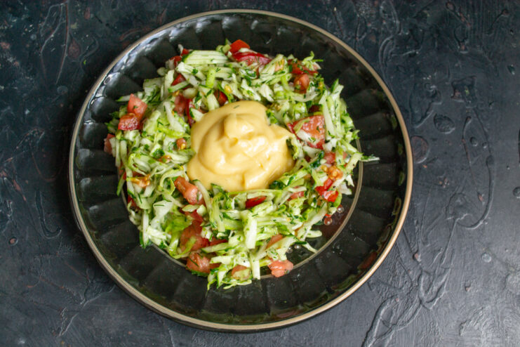 Shaping the Salad Ring Vegetable salad arranged in a ring shape on a black plate with thick mayonnaise in the center.