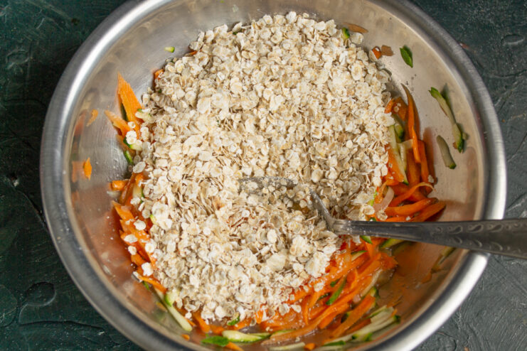 Adding quick oats to the vegetables Quick oats added to the grated vegetable mixture