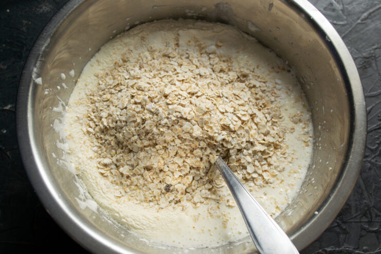 Adding rolled oats Quick-cooking rolled oats added to the dough in a bowl