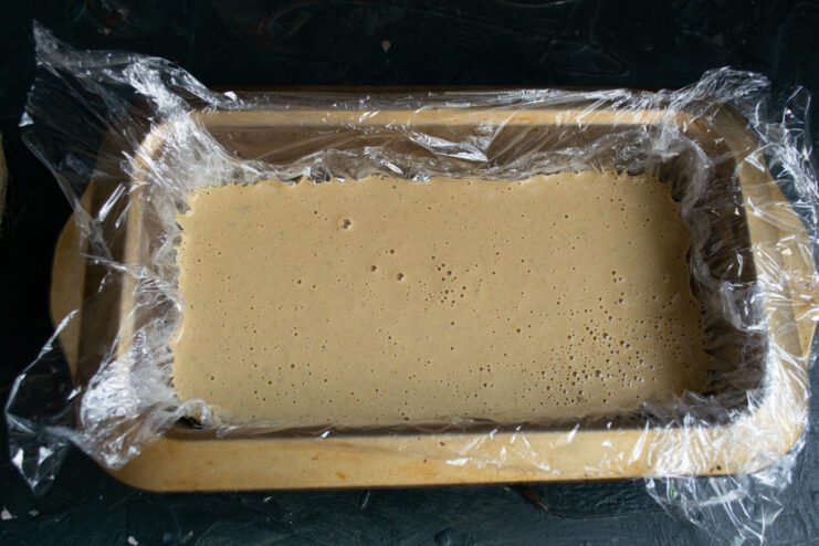 Pouring into the mold Pouring the liquid pâté mixture into a rectangular loaf pan lined with plastic wrap.