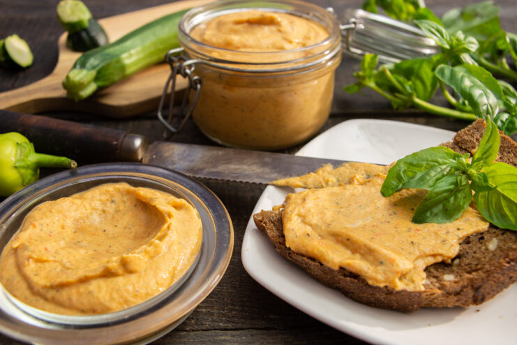 Zucchini and cream cheese sandwich spread on a slice of bread with basil