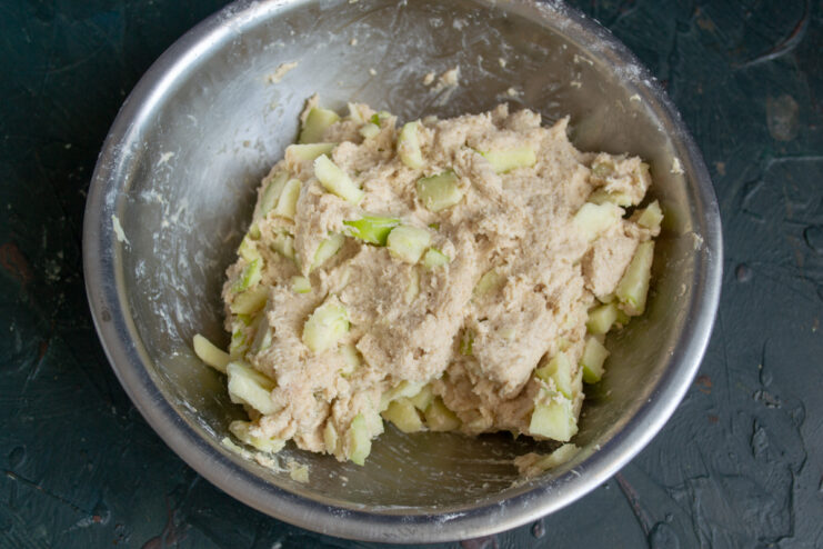 Dough mixed with scattered apple pieces