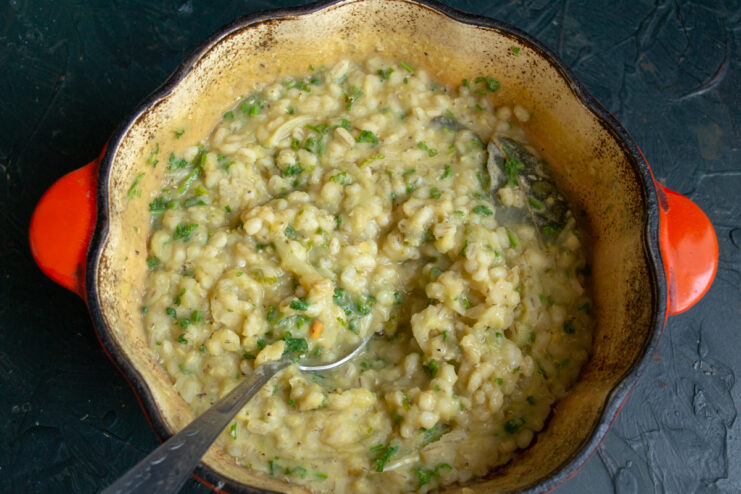 Mixing the Finished Kulesh Stirring the finished kulesh with fresh herbs and onions in a pot