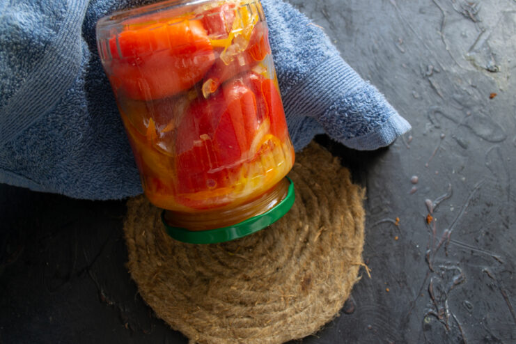 Cooling the sterilized jars Upside-down sealed glass jar of stuffed peppers covered with a towel