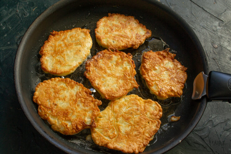 Frying fritters until golden brown Flipped golden-brown onion fritters cooking in a pan.