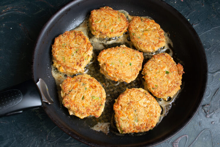 Flipped golden salmon patties cooking in a pan