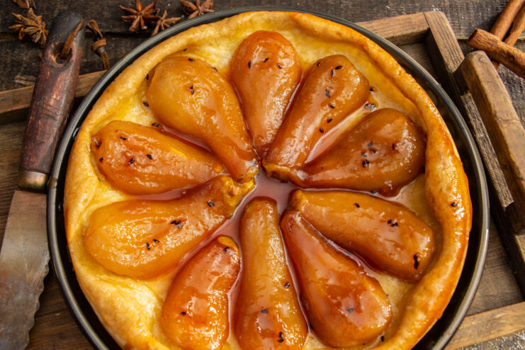 Finished upside-down pear tart with caramel on a rustic wooden background