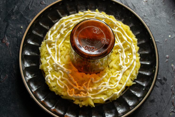 Forming the ring First layer of grated potatoes arranged around a glass jar on a plate