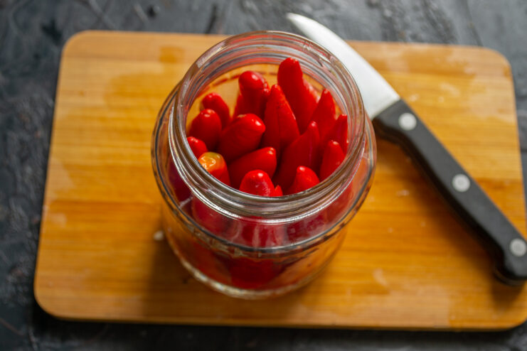 Filling the jar Tightly packed red chili peppers standing upright in a glass jar