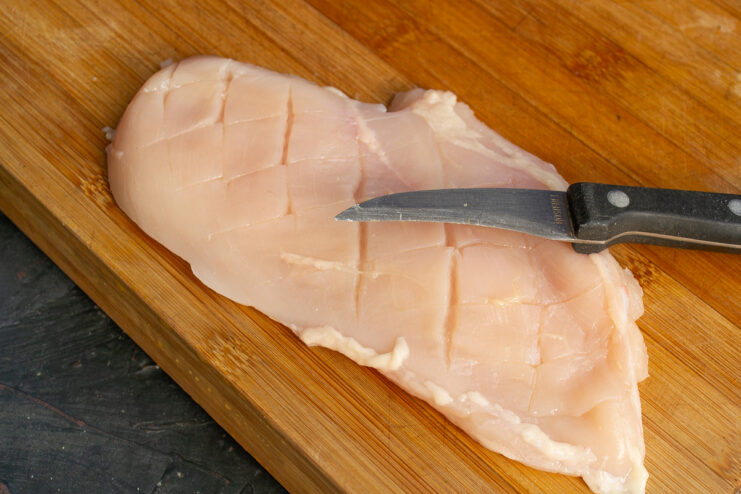 Scoring the chicken fillet Raw chicken breast fillet scored in a crosshatch pattern