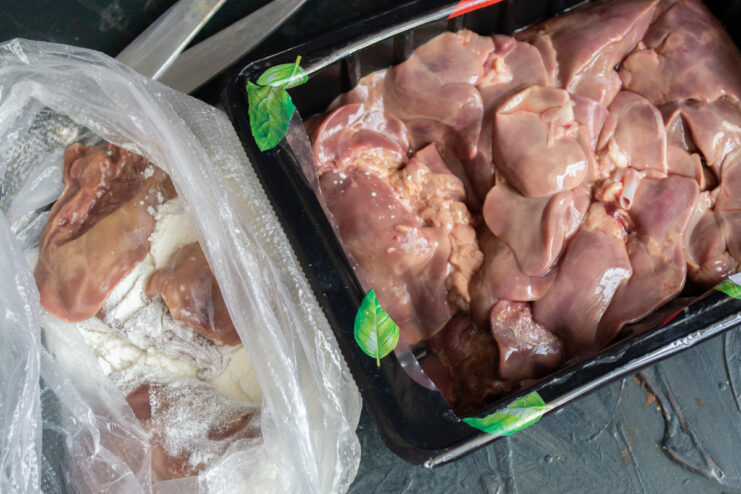 Coating the Chicken Livers Raw chicken livers being coated in cornstarch inside a plastic bag