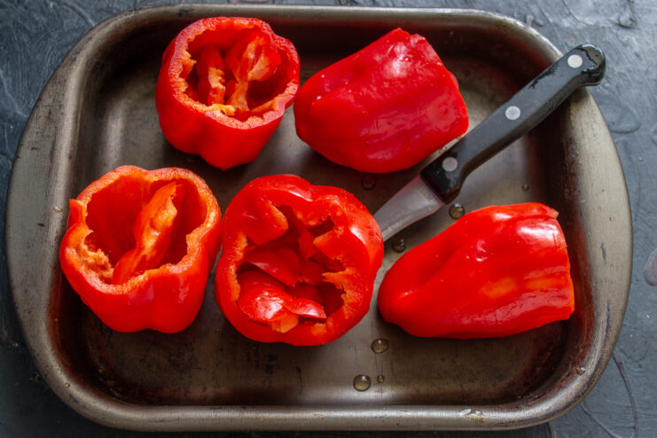 Prepping the bell peppers Prepped and cored red bell peppers arranged on a baking sheet
