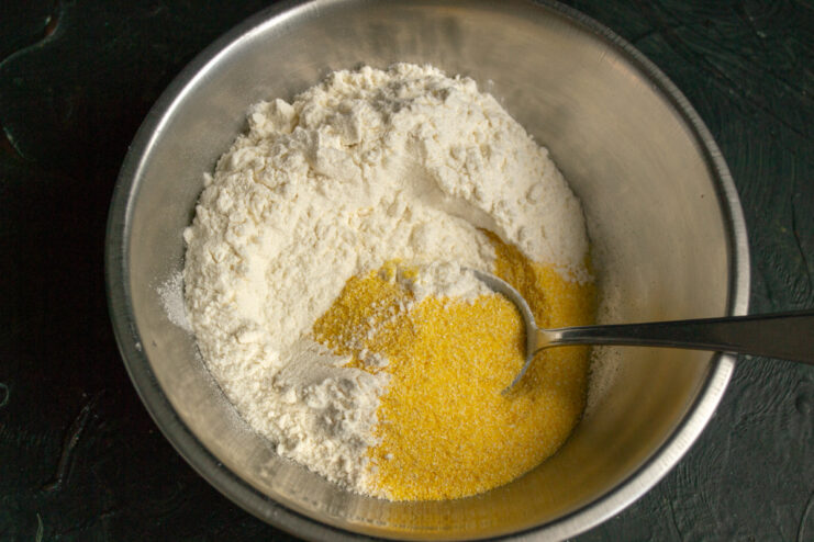 Dry ingredients Polenta and whole wheat flour in a metal mixing bowl ready to be mixed.
