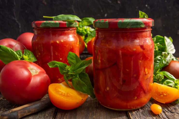 Glass jars filled with chopped tomatoes in thick natural juice for winter storage