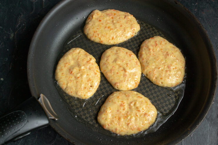 Frying The Fritter Base Small portions of potato batter frying in hot oil in a skillet