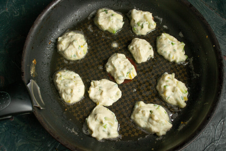 Small portions of fritter batter frying in a hot skillet