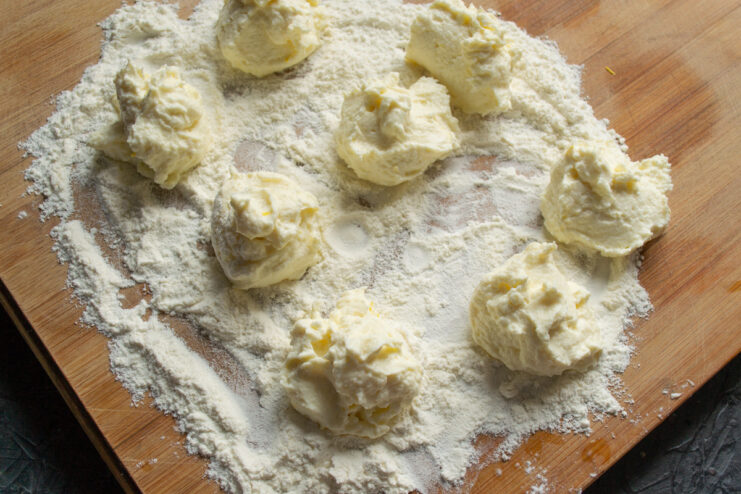 Portioned pieces of cheese dough on a flour-dusted board