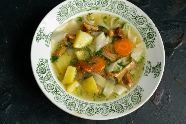 Serving the soup A portion of hot chanterelle noodle soup in a patterned bowl